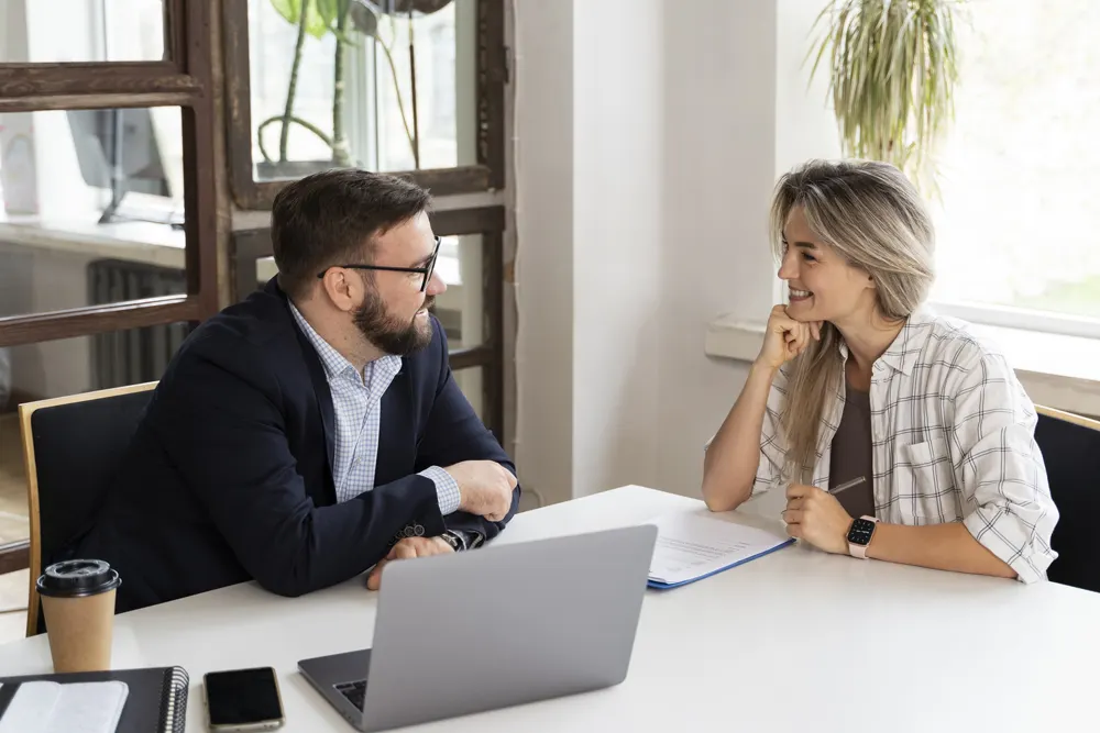 A broker and client talking through plan options across the desk