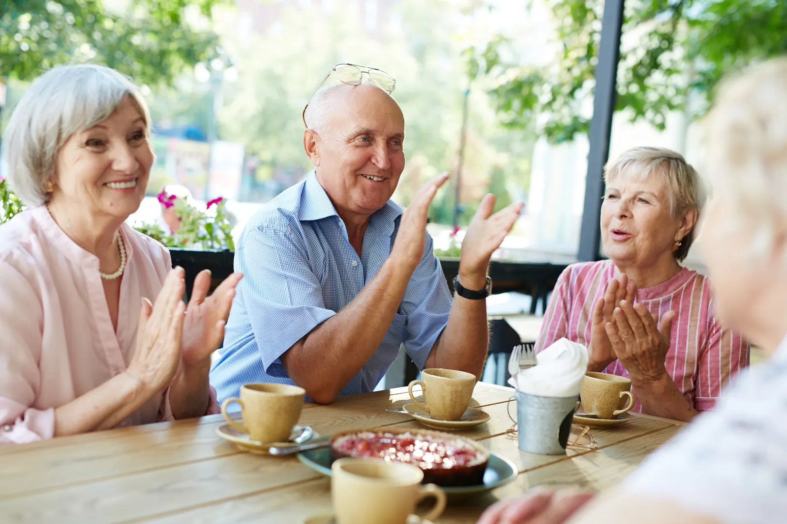 Seniors laughing together over coffee outdoors